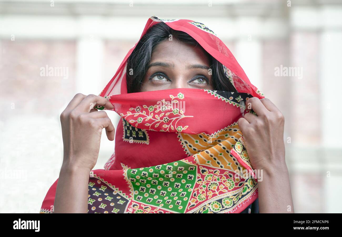 Schöne indische Frau mit traditionellem indischen Saree-Kostüm, Schleier bedeckt ihr Gesicht und enthüllt nur die Augen. Stockfoto