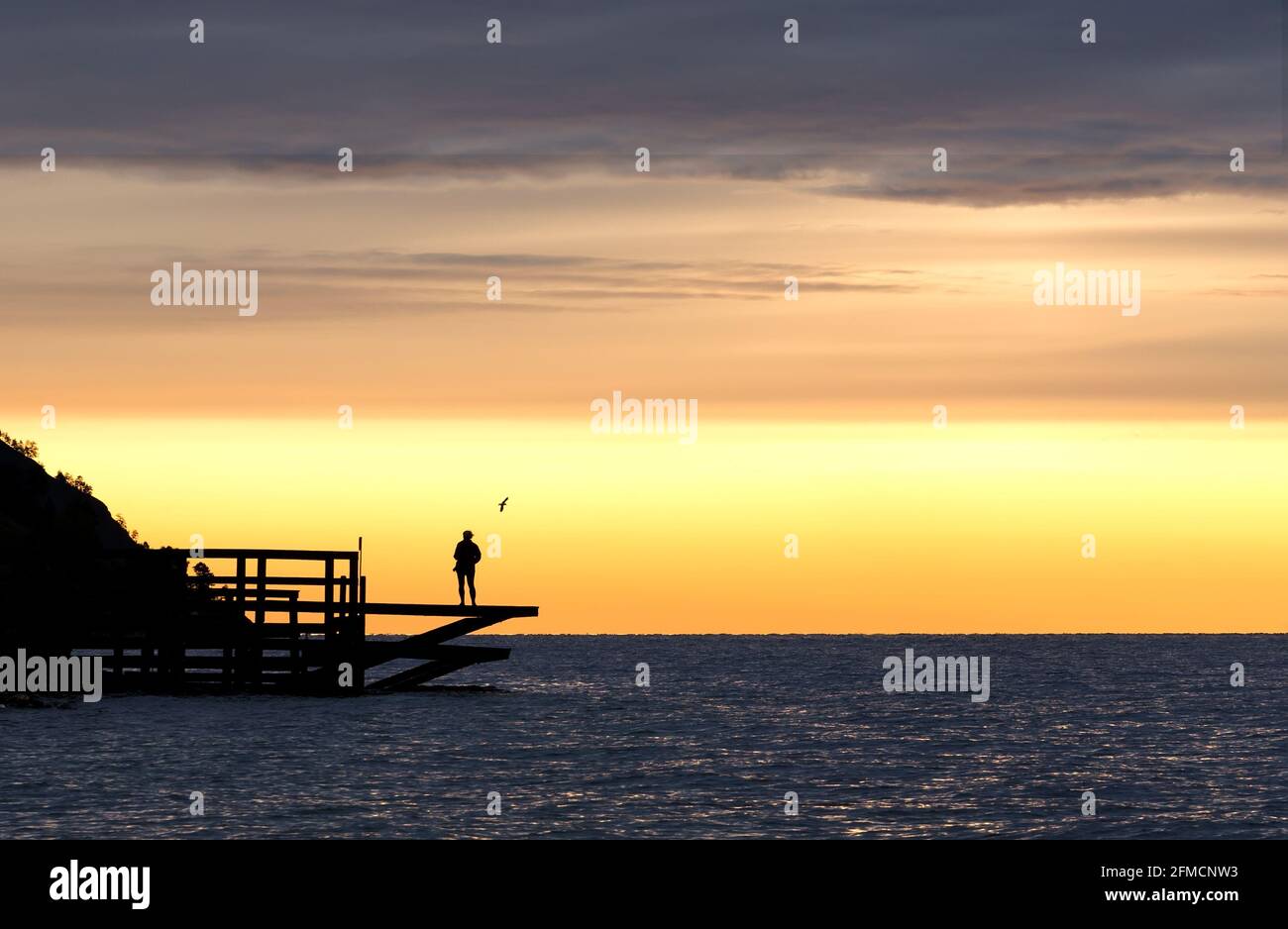 Schöner gelber und blauer Sonnenaufgang am frühen Morgen auf dem See oder Meer mit schwarzen Silhouetten. Hintergrund bei Sonnenuntergang oder Sonnenaufgang mit Kopierplatz. Morgens oder tr Stockfoto