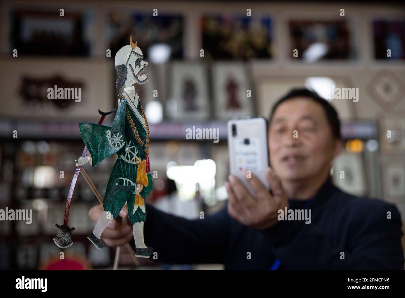 Huazhou, Chinas Provinz Shaanxi. Mai 2021. Ein Tourist fotografiert eine Schattenpuppe während einer Ausstellung im Bezirk Huazhou der Stadt Weinan, nordwestlich der chinesischen Provinz Shaanxi, am 8. Mai 2021. Das Schattenspiel, auch als Schattenpuppenspiel bekannt, ist eine traditionelle chinesische Volkskunst. 2011 wurde das chinesische Schattenpuppenspiel in die UNESCO-Repräsentativliste des immateriellen Kulturerbes der Menschheit aufgenommen. Quelle: Wei Xiang/Xinhua/Alamy Live News Stockfoto