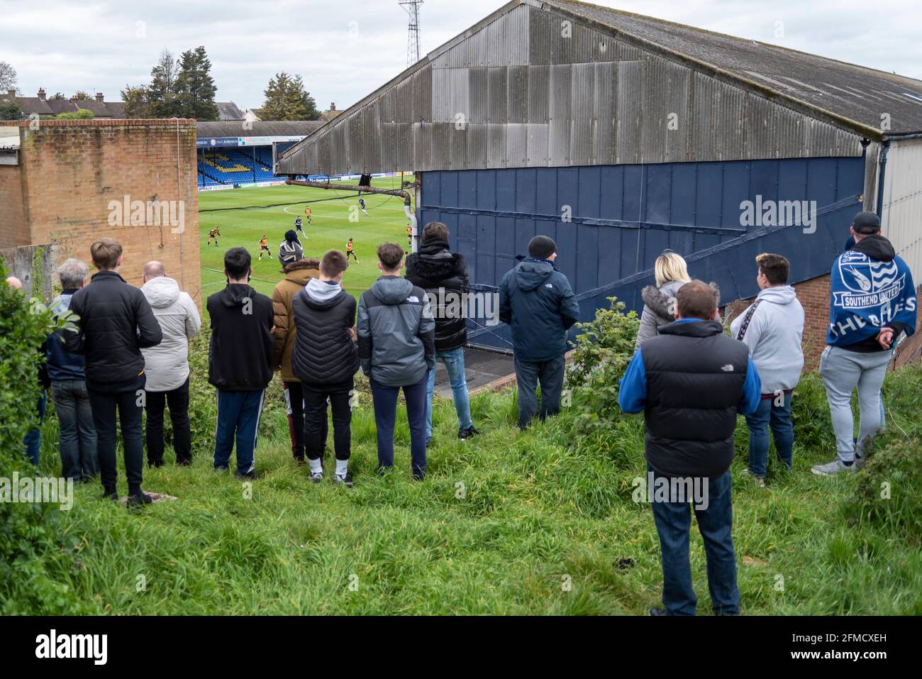 Roots Hall, Southend on Sea, Essex, Großbritannien. Mai 2021. Im Fußballverein Southend United, der aus der zweiten Liga in den Status einer anderen Liga abgesetzt wurde, findet ein Protest statt. Die Fans beschuldigen den Vorsitzenden Ron Martin, dass er sich auf die Entwicklung von Roots Hall in Wohnungen und einen Umzug in ein geplantes neugebautes Stadion auf Fossetts Farm auf Kosten des Teams konzentriert hat. Unterstützer befürchten, dass Roots Hall ohne Garantie für ein neues Zuhause entwickelt werden könnte, was die Zukunft des Clubs riskiert. Besucher Newport County wetteifern um einen Play-off-Platz. Fans finden einen Aussichtspunkt, um das Spiel während der COVID 19 zu beobachten Stockfoto