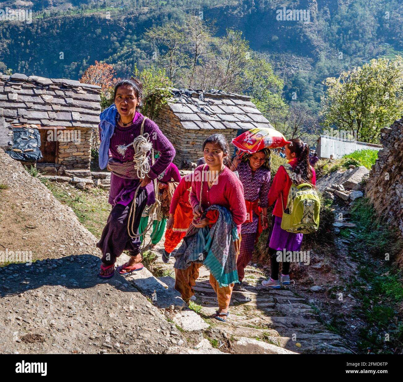 Fröhliche lächelnde Frauen und Kinder, die den steilen Weg hinaufklettern Zum Dorf Supi im Uttarakhand Himalaya Nordindien Stockfoto