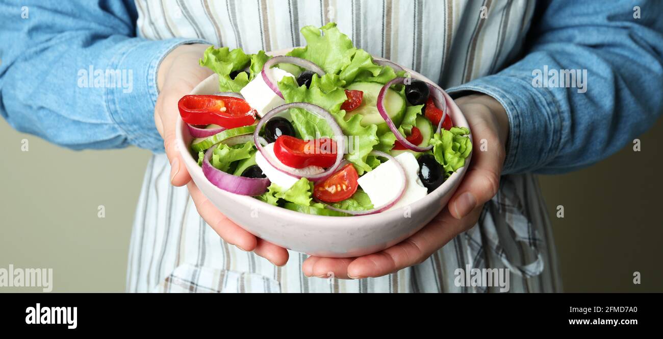 Frau auf der Schürze hält eine Schüssel mit griechischem Salat Stockfoto