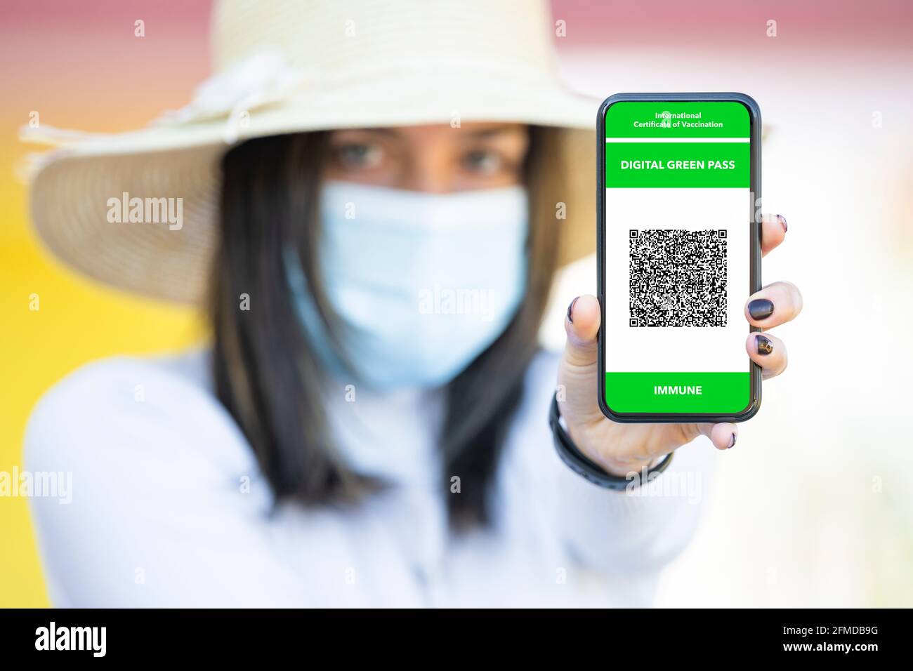 Defokussiertes junges Mädchen mit einem Smartphone und einem Green Pass. Das Digital Green Certificate erleichtert den sicheren freien Bewegung Stockfoto