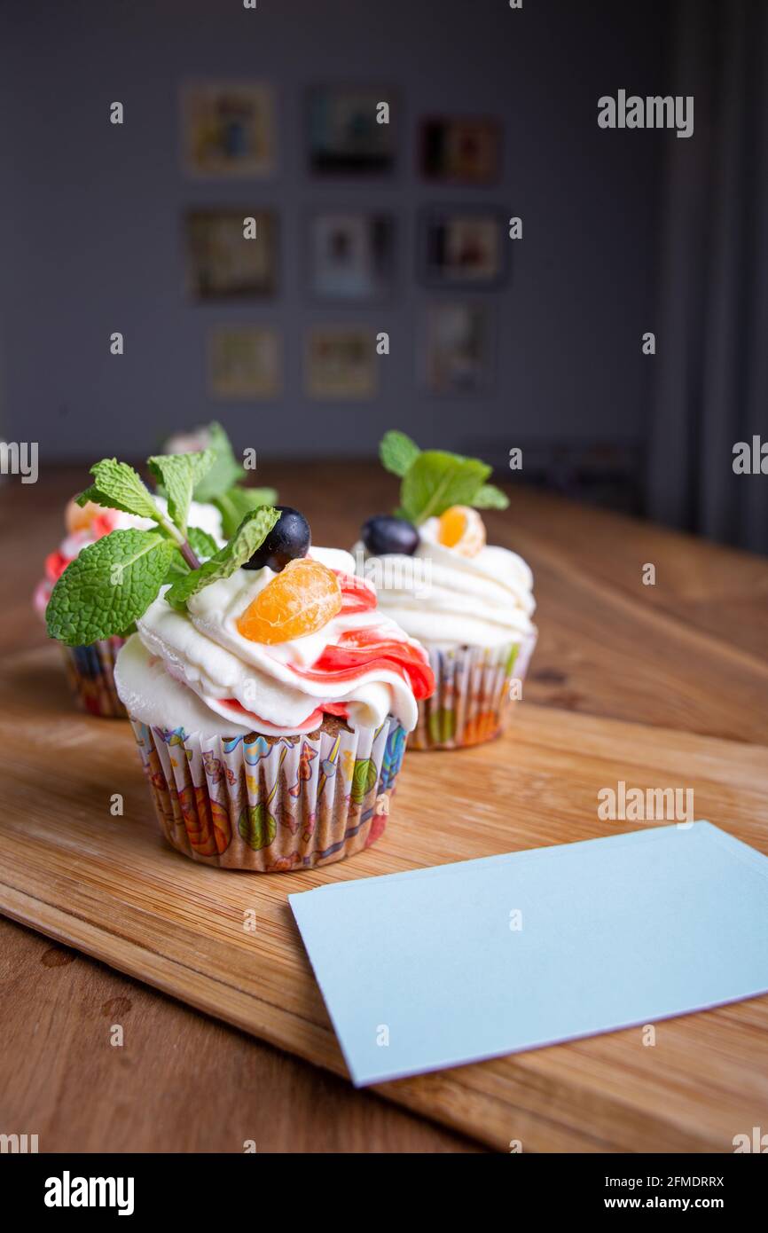 Drei Cupcakes auf einem Holzhintergrund mit Visitenkarten für Ihr Design Stockfoto