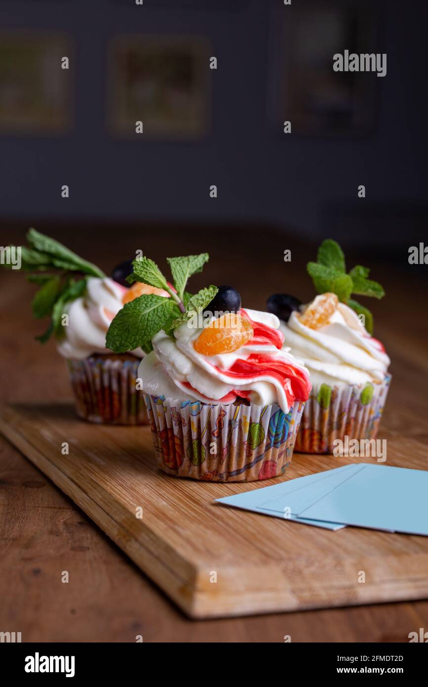 Drei Cupcakes auf einem Holzhintergrund mit Visitenkarten für Ihr Design Stockfoto