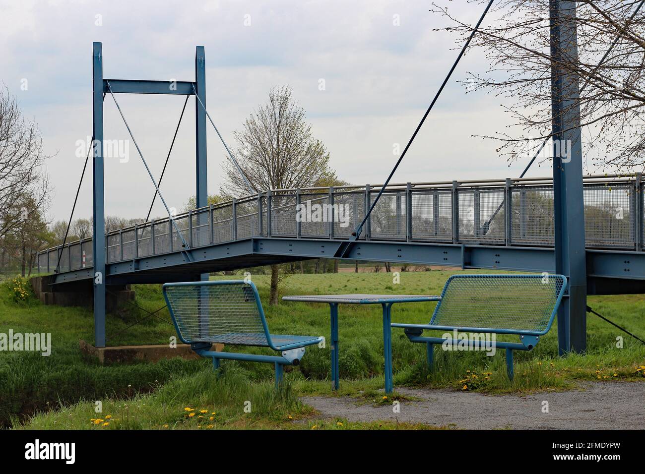 Blaue Picknickbänke und Tisch vor einer blauen Brücke für Radfahrer und Fußgänger. Beide bestehen aus Eisen und Stahl Stockfoto