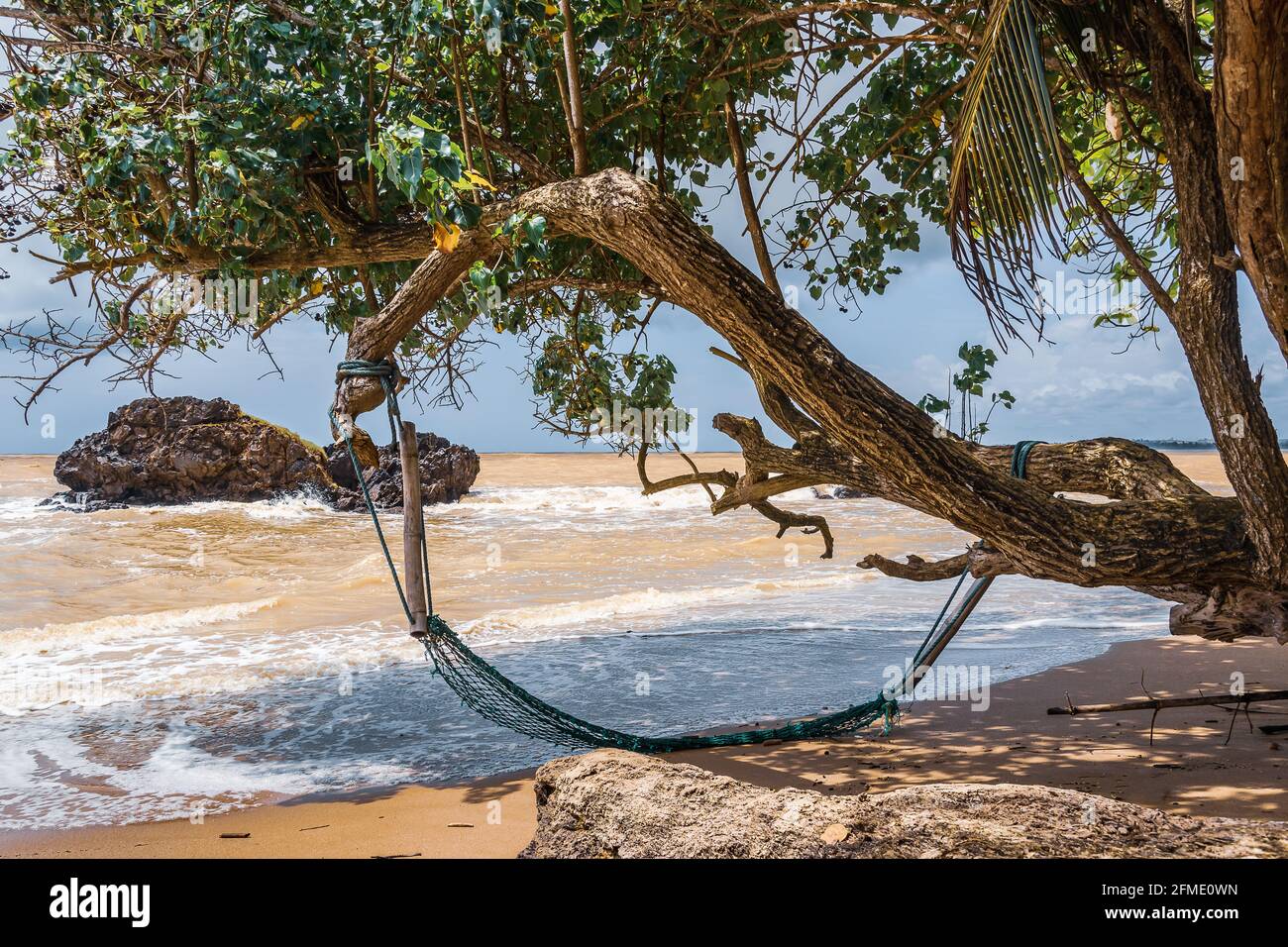An einem leeren Strand in Axim Ghana West Africa hing eine verlassene Hängematte an einem Baum. Stockfoto