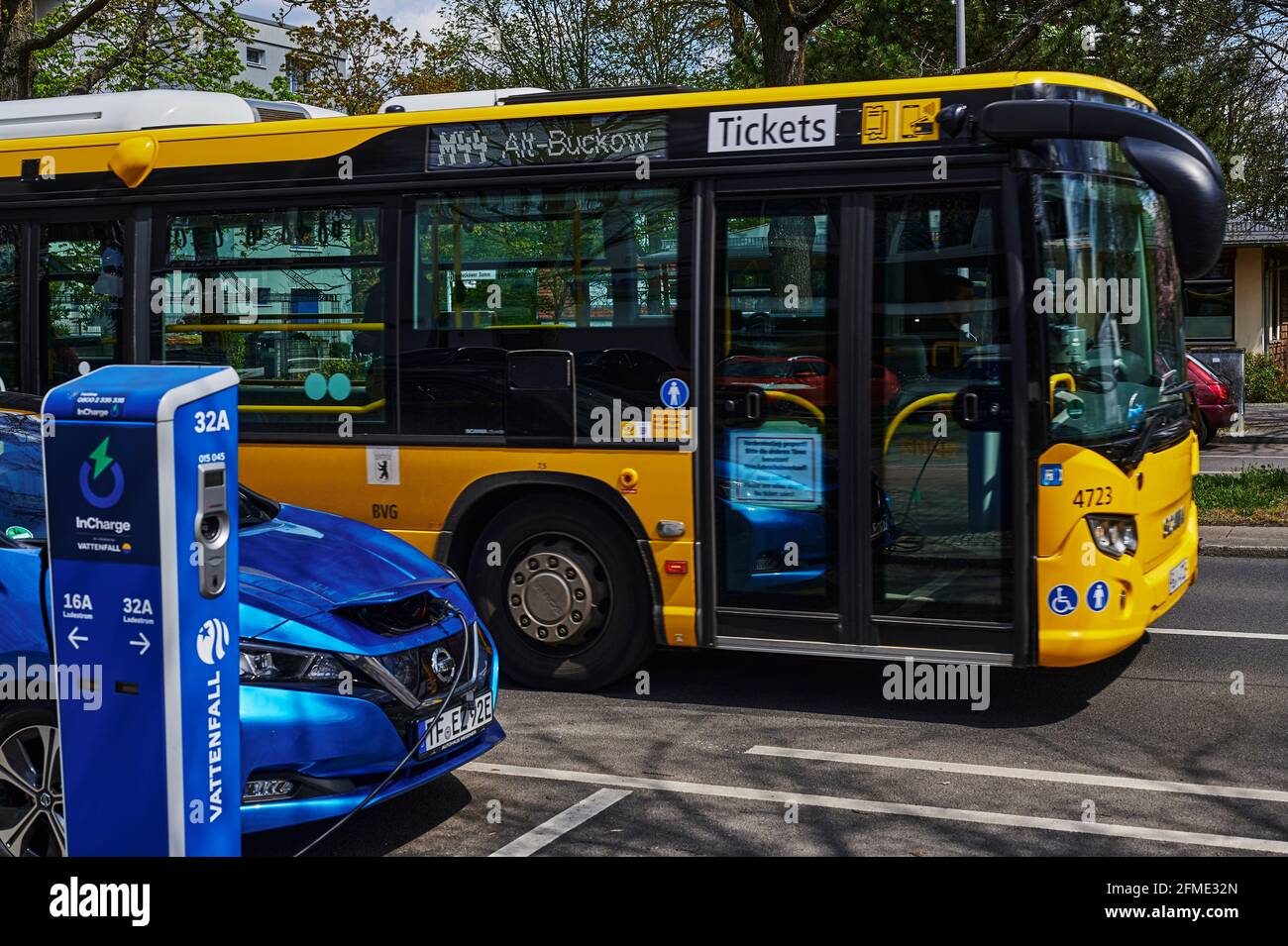 Berlin, Deutschland - 8. Mai 2021: Ein umweltfreundliches Elektroauto an einer Ladestation und ein Bus des öffentlichen Nahverkehrs, der etwas unscharf ist. Der Fokus Stockfoto