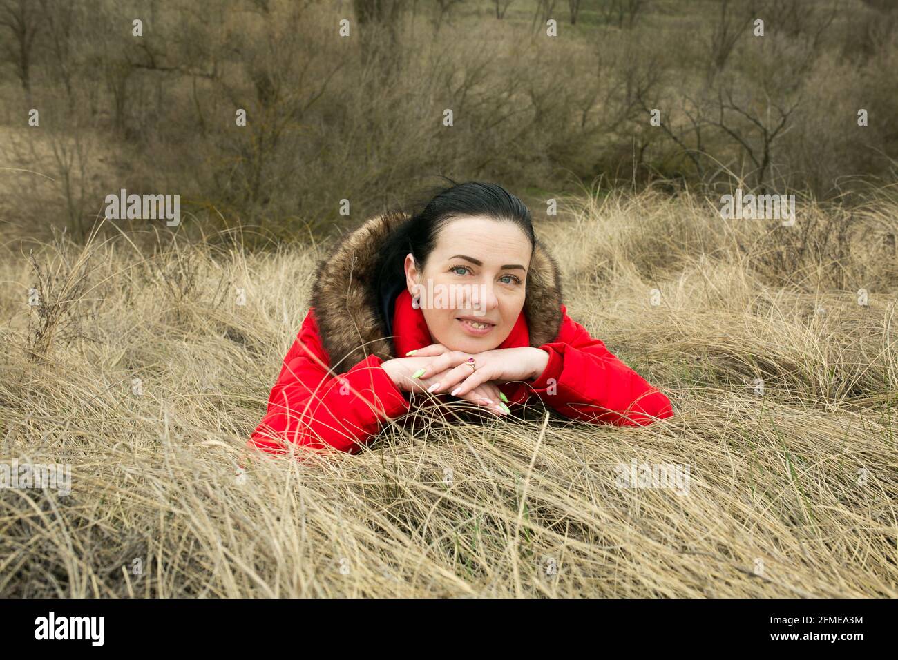 Dnepropetrovsk, Ukraine - 04.08.2021 - EINE schöne schwarzhaarige Frau liegt im Frühjahr auf dem gelben Gras. Die Frau genießt die Frühlingssonne und geht Stockfoto
