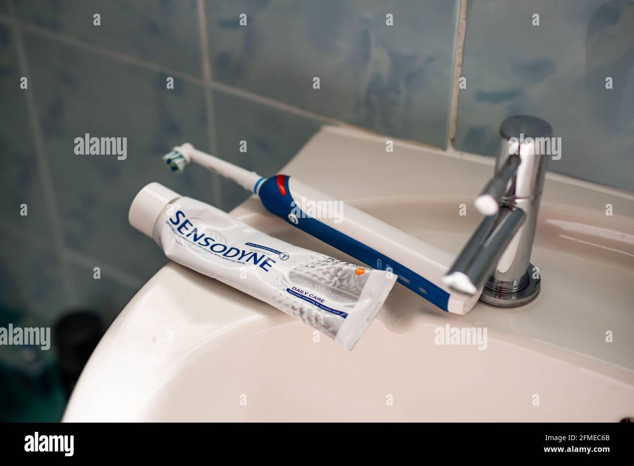 Nahaufnahme und selektiver Fokus auf eine Sensodyne-Röhre Zahnpasta und  eine elektrische Zahnbürste Oral B auf einer weißen Waschbecken im  Badezimmer Stockfotografie - Alamy