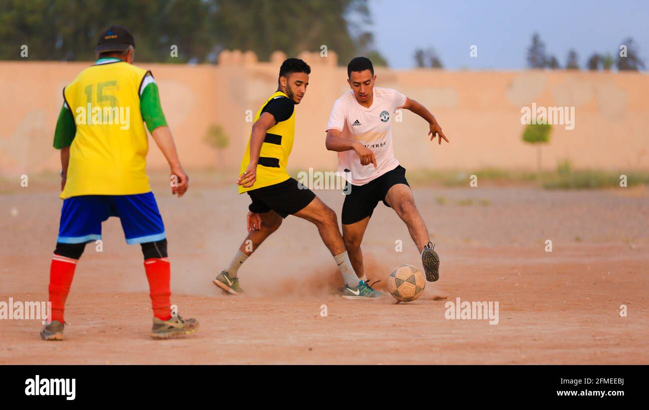Marrakesch, Marokko - 25. APRIL 2021 : Männer spielen Fußball auf einem staubigen Feld Marrakesch in Marokko Stockfoto