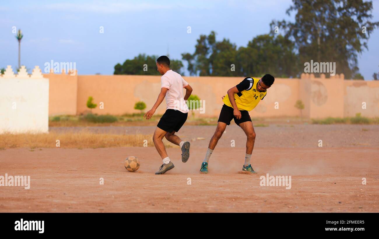 Marrakesch, Marokko - 25. APRIL 2021 : Männer spielen Fußball auf einem staubigen Feld Marrakesch in Marokko Stockfoto