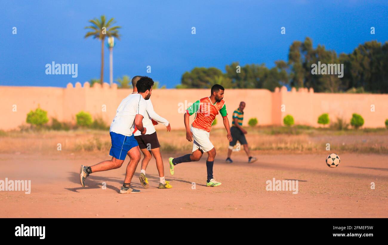 Marrakesch, Marokko - 25. APRIL 2021 : Männer spielen Fußball auf einem staubigen Feld Marrakesch in Marokko Stockfoto
