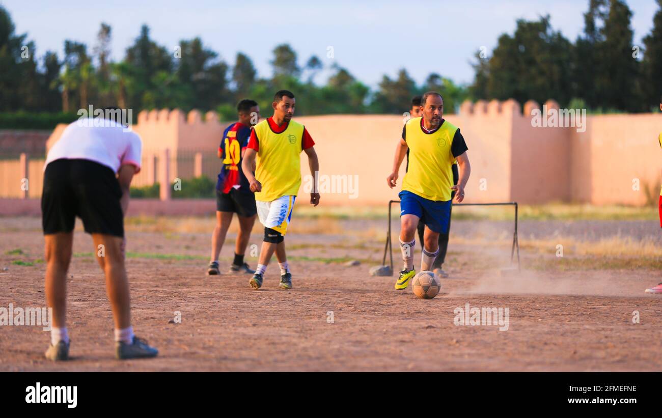 Marrakesch, Marokko - 25. APRIL 2021 : Männer spielen Fußball auf einem staubigen Feld Marrakesch in Marokko Stockfoto
