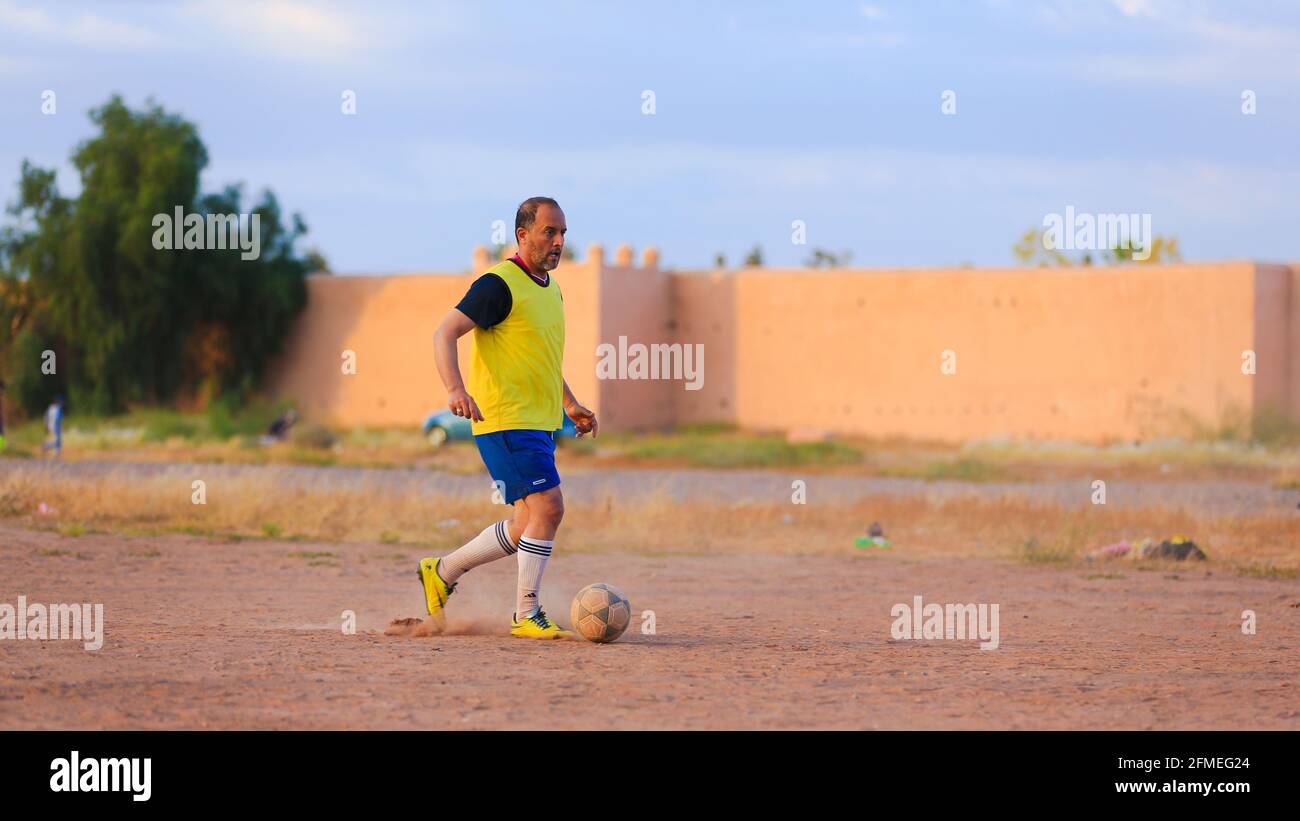 Marrakesch, Marokko - 25. APRIL 2021 : Männer spielen Fußball auf einem staubigen Feld Marrakesch in Marokko Stockfoto
