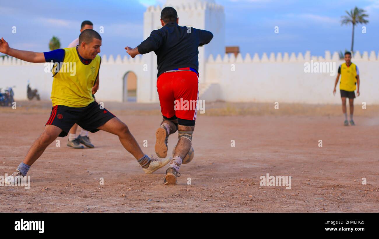 Marrakesch, Marokko - 25. APRIL 2021 : Männer spielen Fußball auf einem staubigen Feld Marrakesch in Marokko Stockfoto