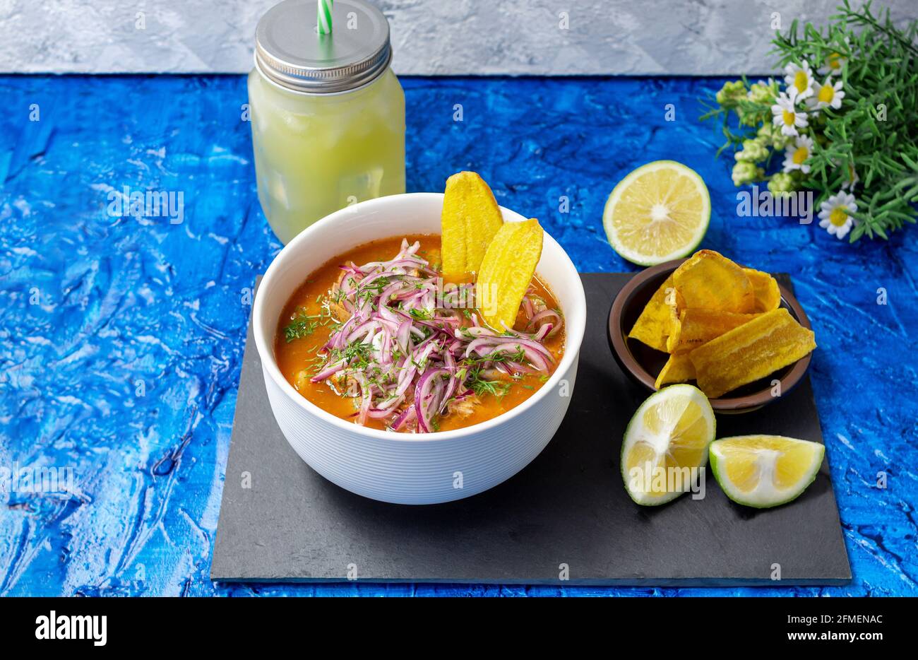 Drei Viertel Foto einer Schüssel mit Encebollado, typisch ecuadorianischen Speisen, zubereitet mit Fisch, Zwiebeln, Zitrone und Yucca auf blauem Hintergrund. In Ecuador Stockfoto