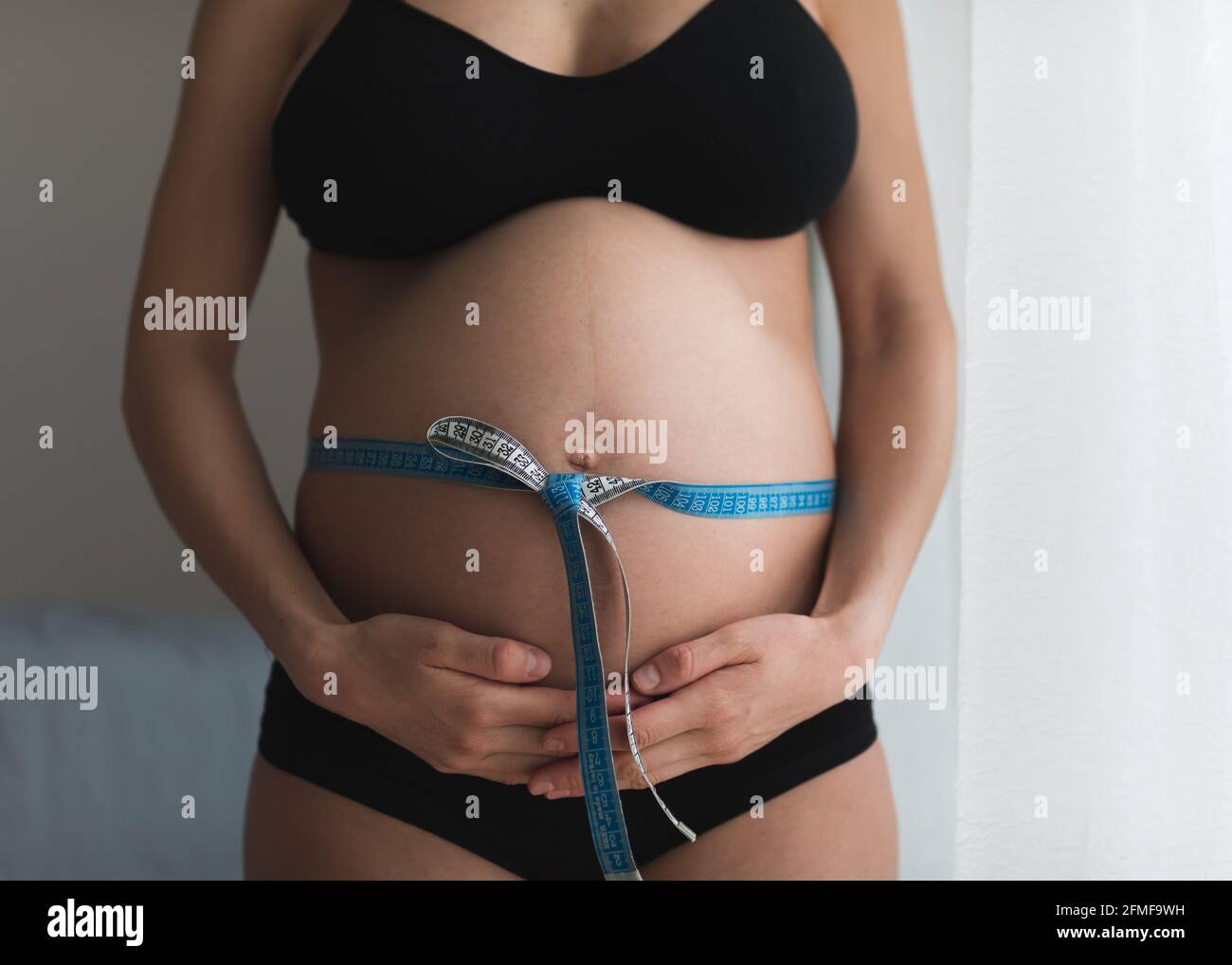 Schwanger Frau messen ihren Bauch mit Maßband. Stockfoto