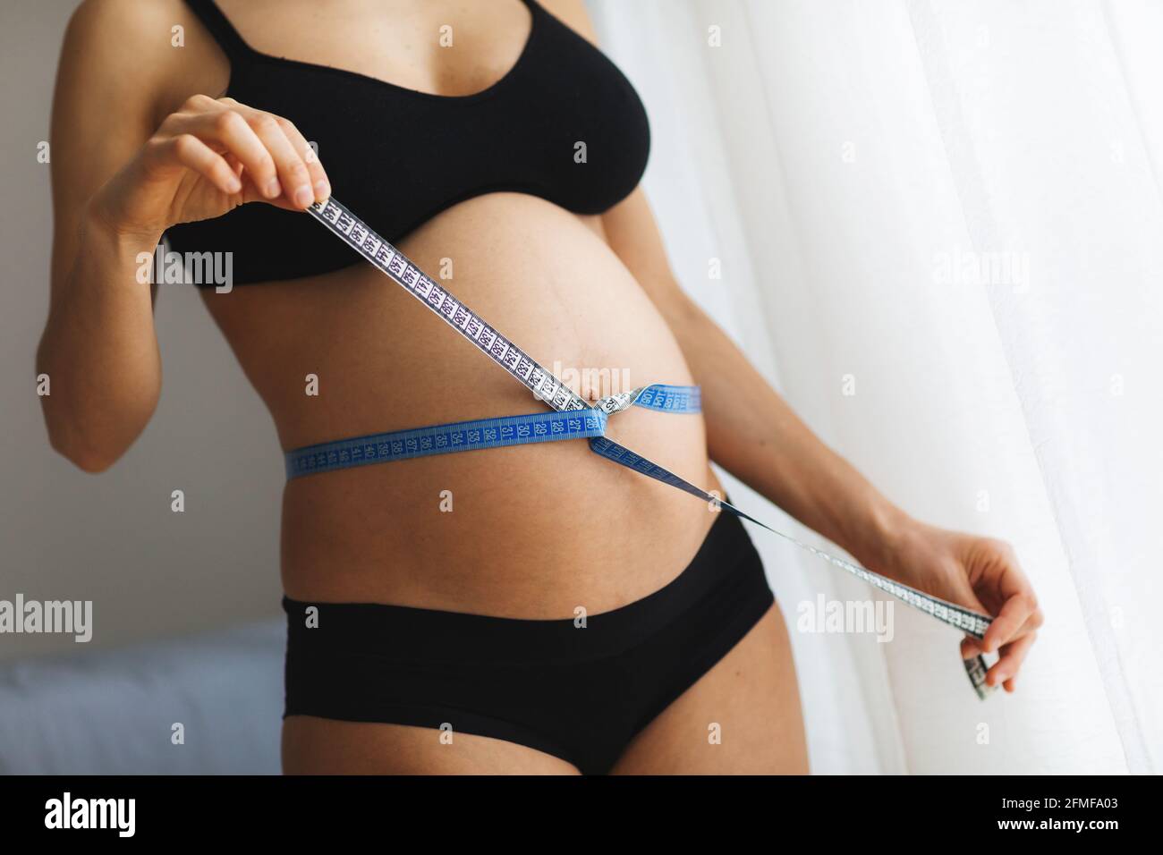 Schwanger Frau messen ihren Bauch mit Maßband. Stockfoto