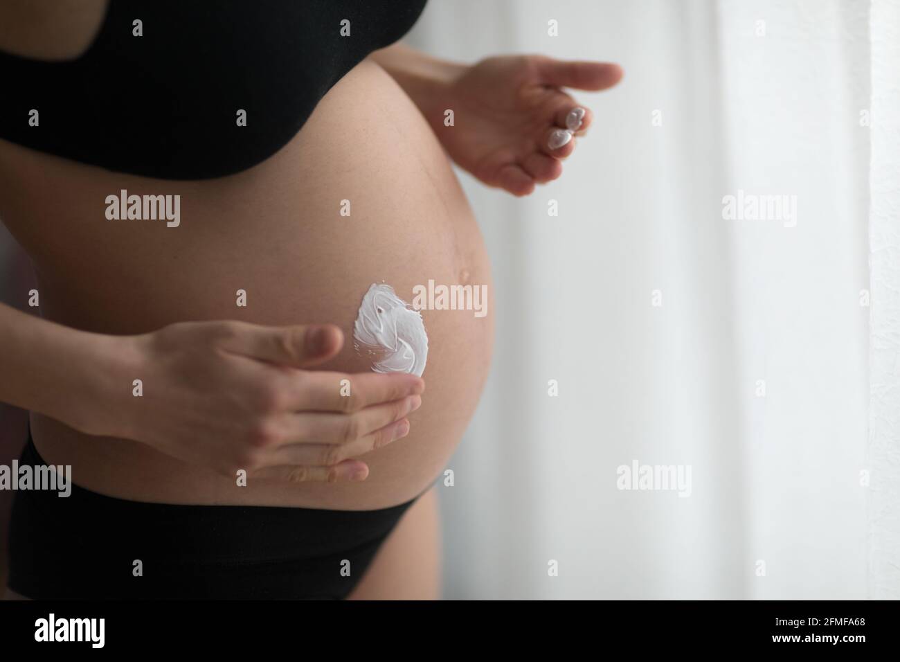 Schwanger Frauen setzen Anti-Stretch-Creme auf ihren Bauch. Kosmetik für feuchtigkeitsspendende oder feuchtigkeitsspendende Haut in der Schwangerschaft. Stockfoto