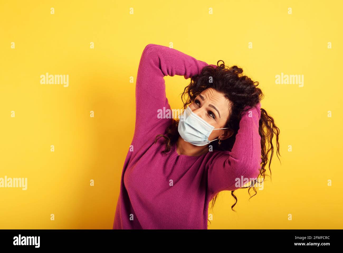 Ängstlicher Ausdruck einer Frau, die Angst hat, das Coronavirus zu fangen. Gelber Hintergrund. Stockfoto