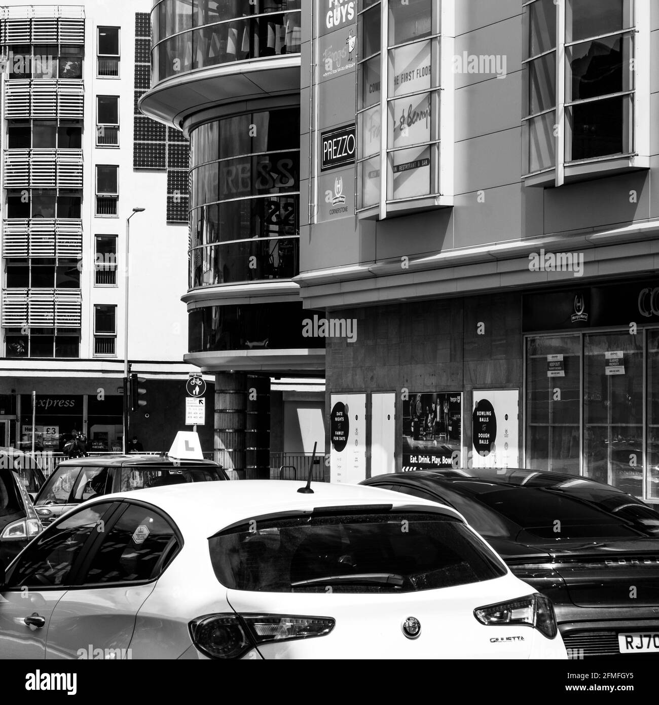 Kingston upon Thames London, Mai 07 2021, Autos oder Fahrzeuge passieren das Handelsgebäude moderner Architektur an EINER High Street im Stadtzentrum Stockfoto