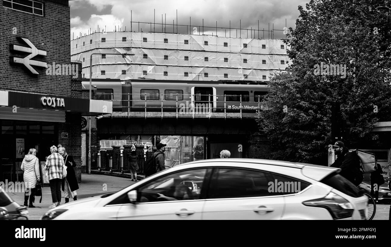 Kingston upon Thames London, Mai 07 2021, Eisenbahnzug über EINE Brücke am Bahnhof Kingston mit EINEM Costa Coffee Shop und Menschen Stockfoto