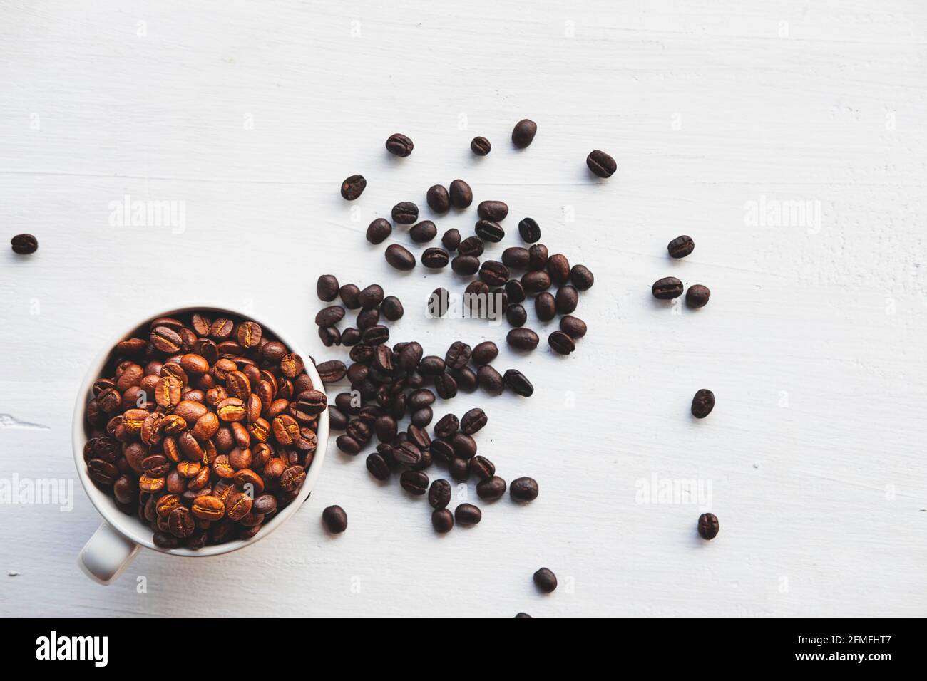 Geröstete Kaffeebohnen in einer Kaffeetasse auf einem weißen Tabelle Stockfoto