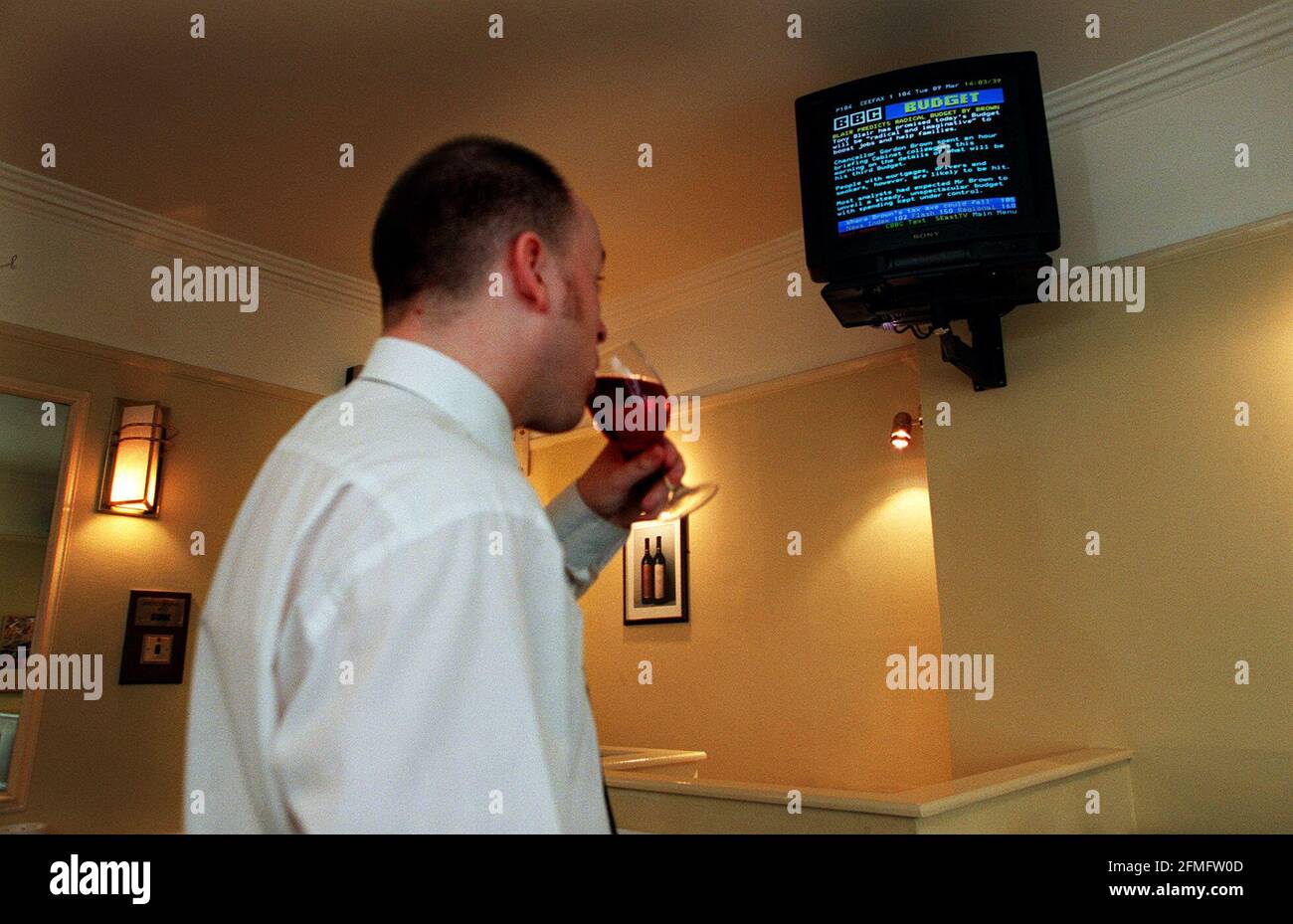 Arbeitshaushalt 1999. Ein Mann, der die Budget-Nachrichten am 1999. März auf Videotext in einer Stadtbar liest, während er ein Glas Wein trinkt. Stockfoto