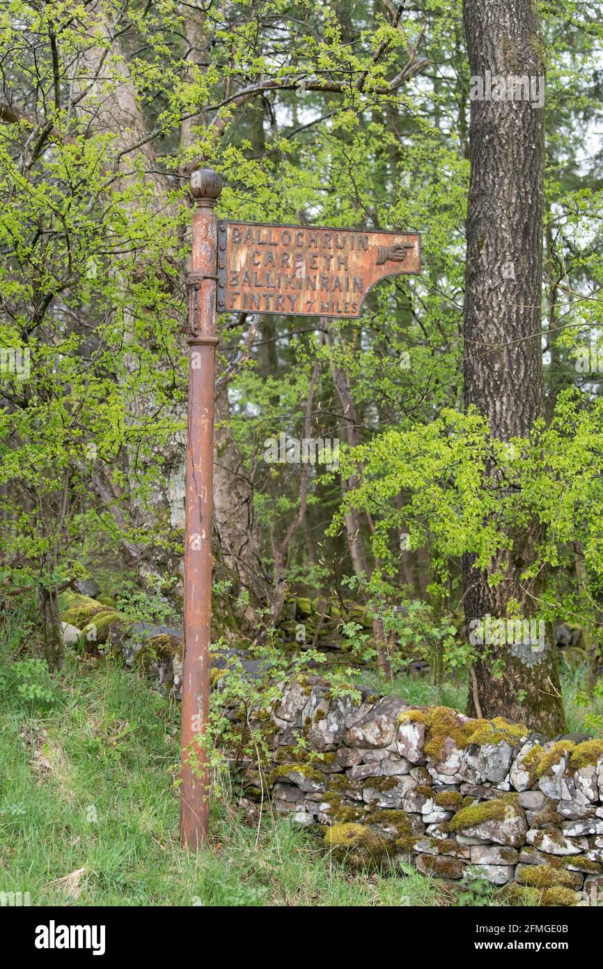 Altes rostiges Straßenschild mit Zeigefinger - Ballochruin, Carbeth, Ballikinrain, Fintry at Balfron Station, Stirling, Scotland, UK Stockfoto