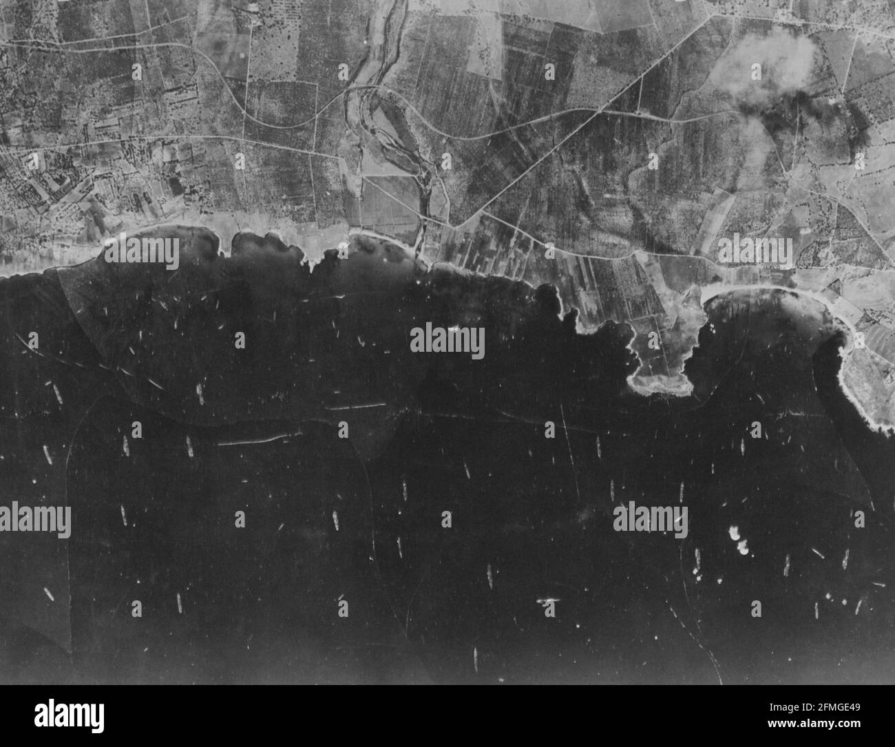 Dieses Bild aus einem fotografischen Aufklärungsflugzeug der US Army Air Forces zeigt einen Teil der südöstlichen sizilianischen Küste, den Tag, an dem die Alliierten einmarschierten. Dutzende unserer Boote sind zu sehen, meist Transporte und Landungsboote. Stockfoto