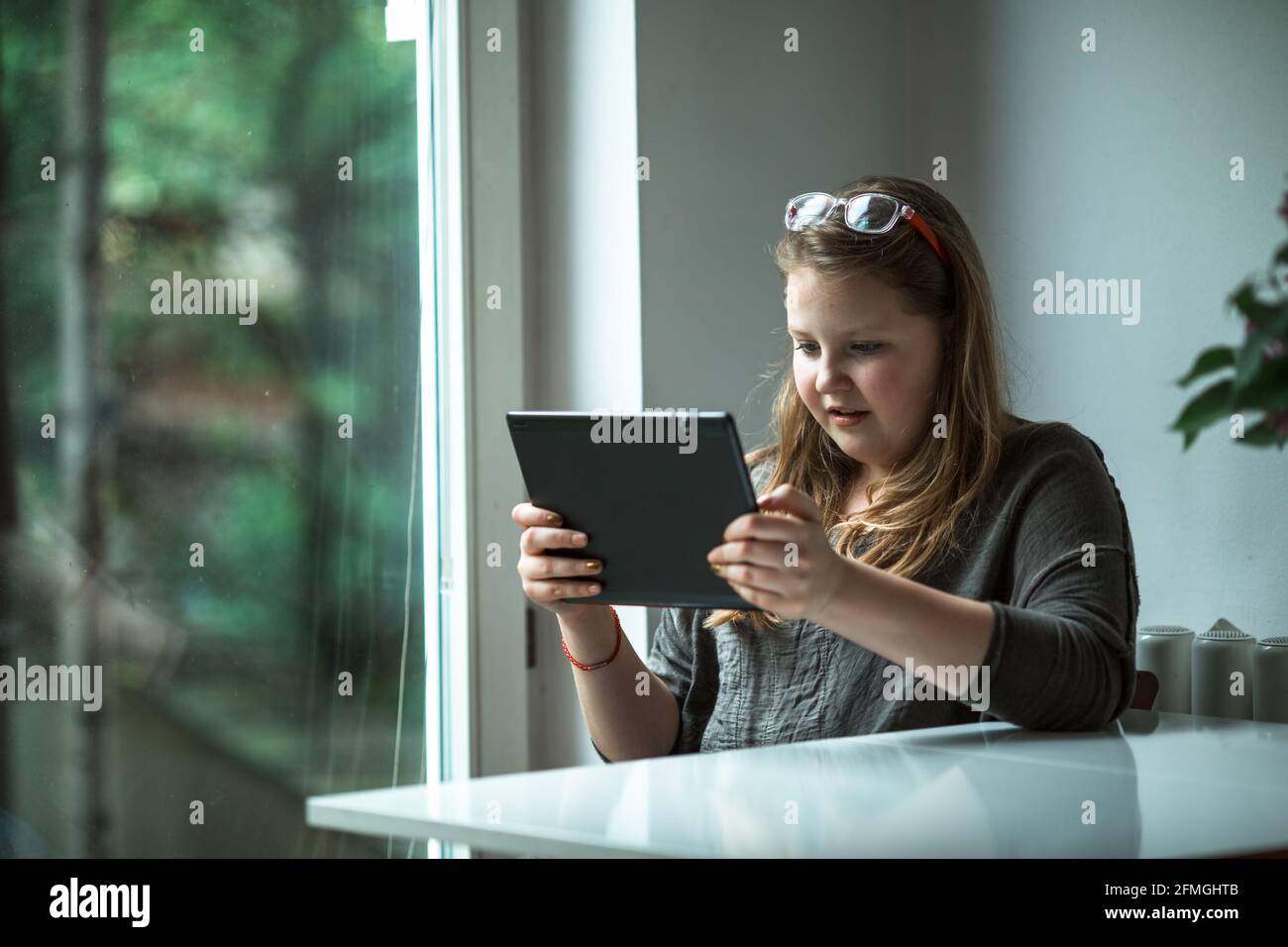 Ein Teenager-Mädchen mit einem Tablet sitzt im Haus. Stockfoto