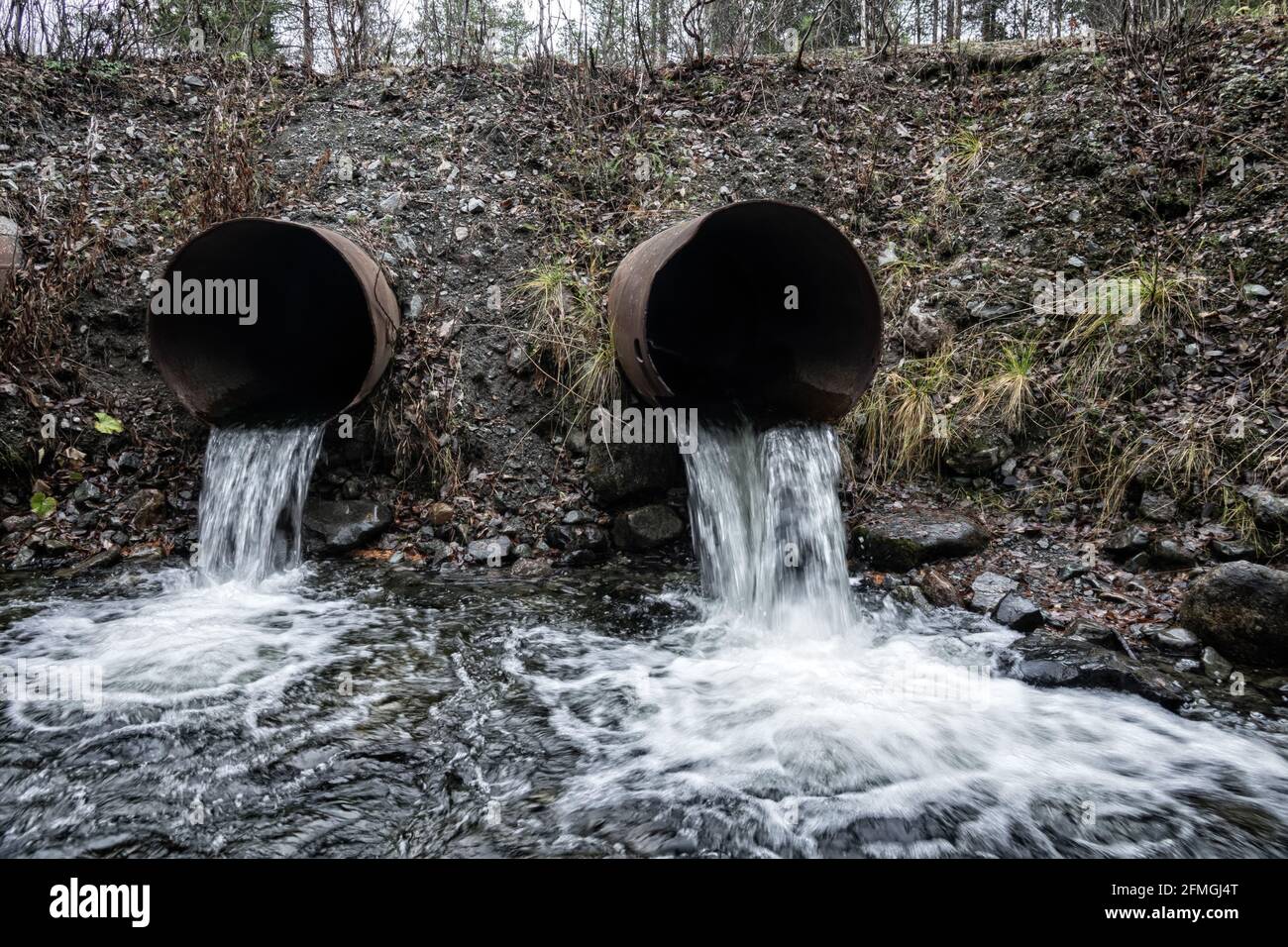 Bundsteg. Abfluss von Wasser aus einem Straßenüberlauf (Wasserentsorgung, Sturmabfluss), zwei Leitungen und langsam fließendes Wasser (direkter Abfluss) Stockfoto