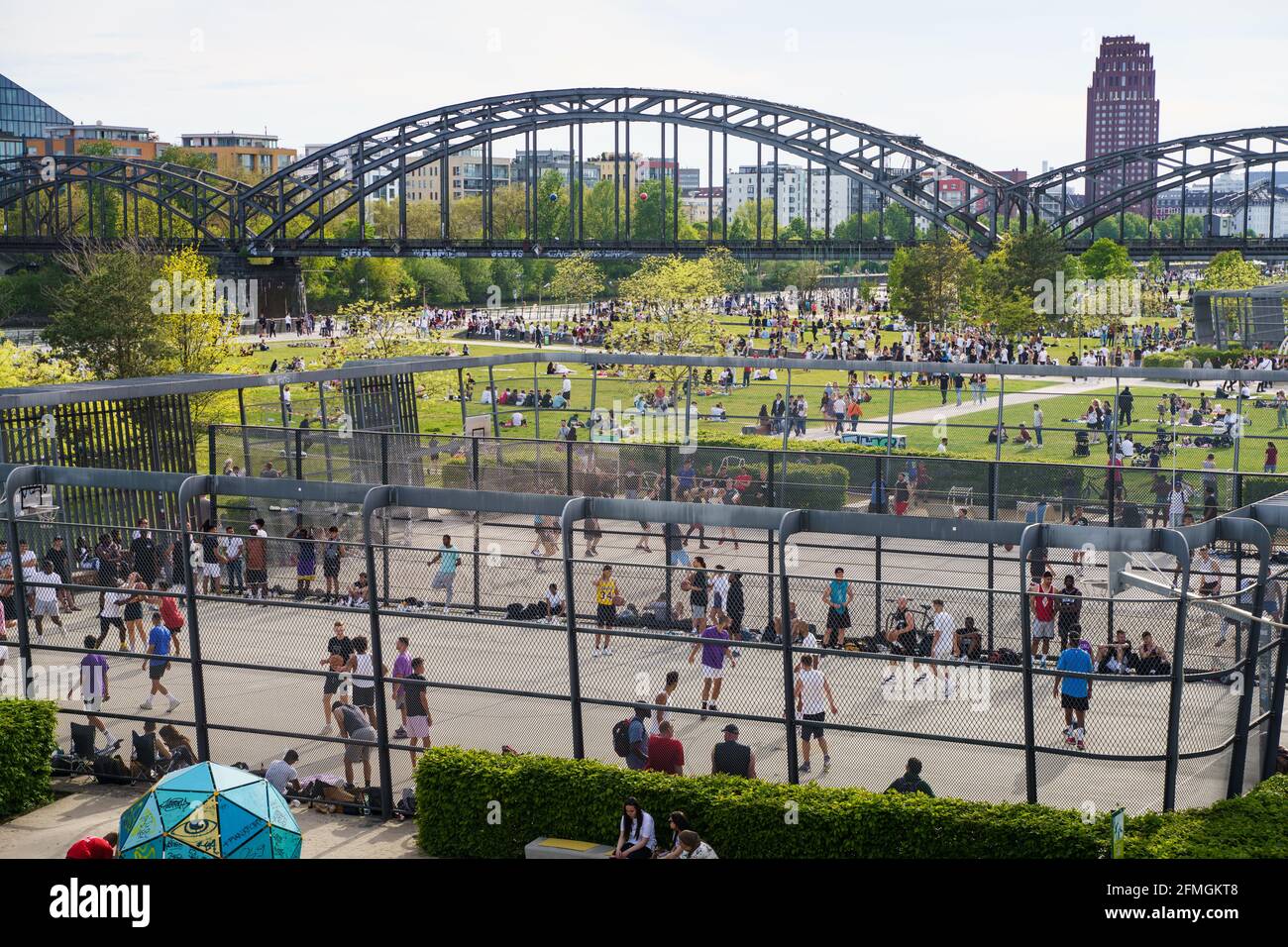 09. Mai 2021, Hessen, Frankfurt/Main: Zahlreiche Menschen tummeln sich bei Sonnenschein und angenehmen Temperaturen auf den Wiesen oder spielen Basketball auf den beliebten Plätzen im Hafenpark. Foto: Frank Rumpenhorst/dpa Stockfoto