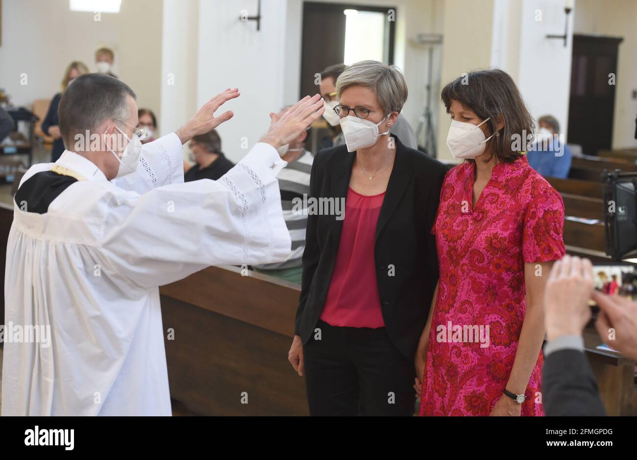 München, Deutschland. Mai 2021. Vikar Wolfgang Rothe segnet das Ehepaar Christine Walter (l.) und Almut Münster während eines katholischen Gottesdienstes mit dem Segen homosexueller Paare im Rahmen einer bundesweiten Kampagne in der Kirche St. Benedikt. Unter dem Motto „#liebegewinnt“ laden Pfarrer in ganz Deutschland um den 10. Mai zu Gottesdiensten ein, in denen homosexuelle Paare gesegnet werden können. Es handelt sich um eine Protestaktion gegen einen kürzlich veröffentlichten Brief, in dem der Vatikan diese Segnungen verboten hat. Quelle: Felix Hörhager/dpa/Alamy Live News Stockfoto