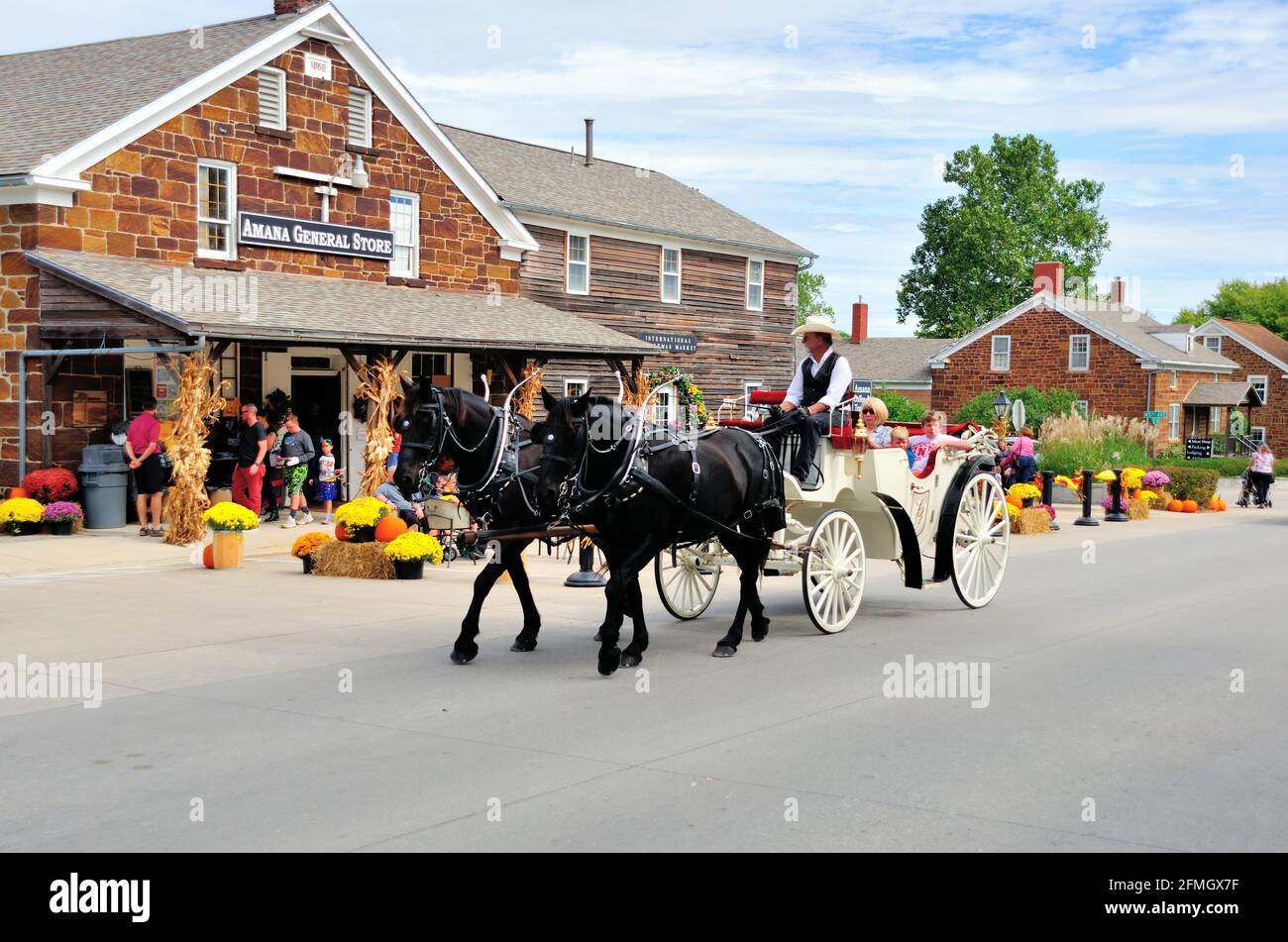 Amana Colonies, Iowa, USA. Eine Pferdekutsche bringt Besucher auf einer Oktoberfestfeier in Amana, Iowa, eine Hauptstraße entlang. Stockfoto