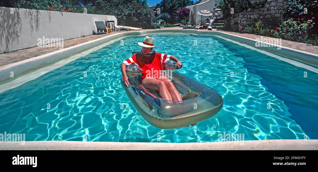 Historisches Archiv 1985 Ansicht aller Lifestyle-Zutaten für ein erfolgreiches portugiesisches Modell freigegeben Familienpaket Sonnenschein Villa Urlaub An der Algarve, einschließlich eines wunderschönen privaten 80iger Swimmingpools in heißem, blauem Himmel, sonnigem Sommerwetter, bei dem sich Mama in der Ferne entspannen kann Sonnenliege neben Pool Teenager Tochter Sonnenbaden auf schwimmenden Sessel lilo und Papa nimmt 80er Jahre Archivfoto von der So waren wir in einem Bild, das fast alles für einen Reiseurlaub im Ausland in Portugal hat Stockfoto