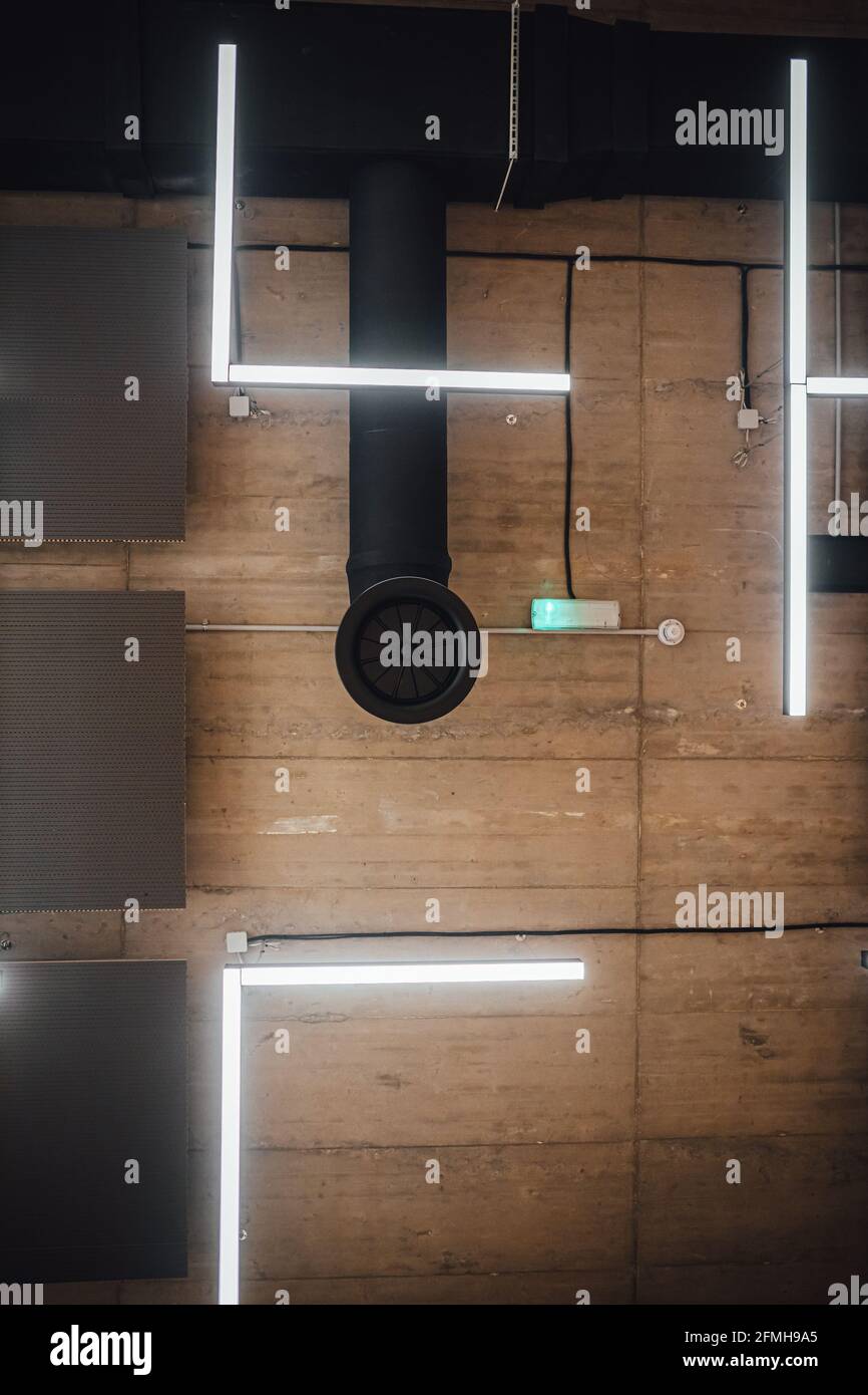 Eine Aufnahme eines modernen LED-Blitzes, der an den Decken hängt, Betonstruktur für Industriegebäude Stockfoto