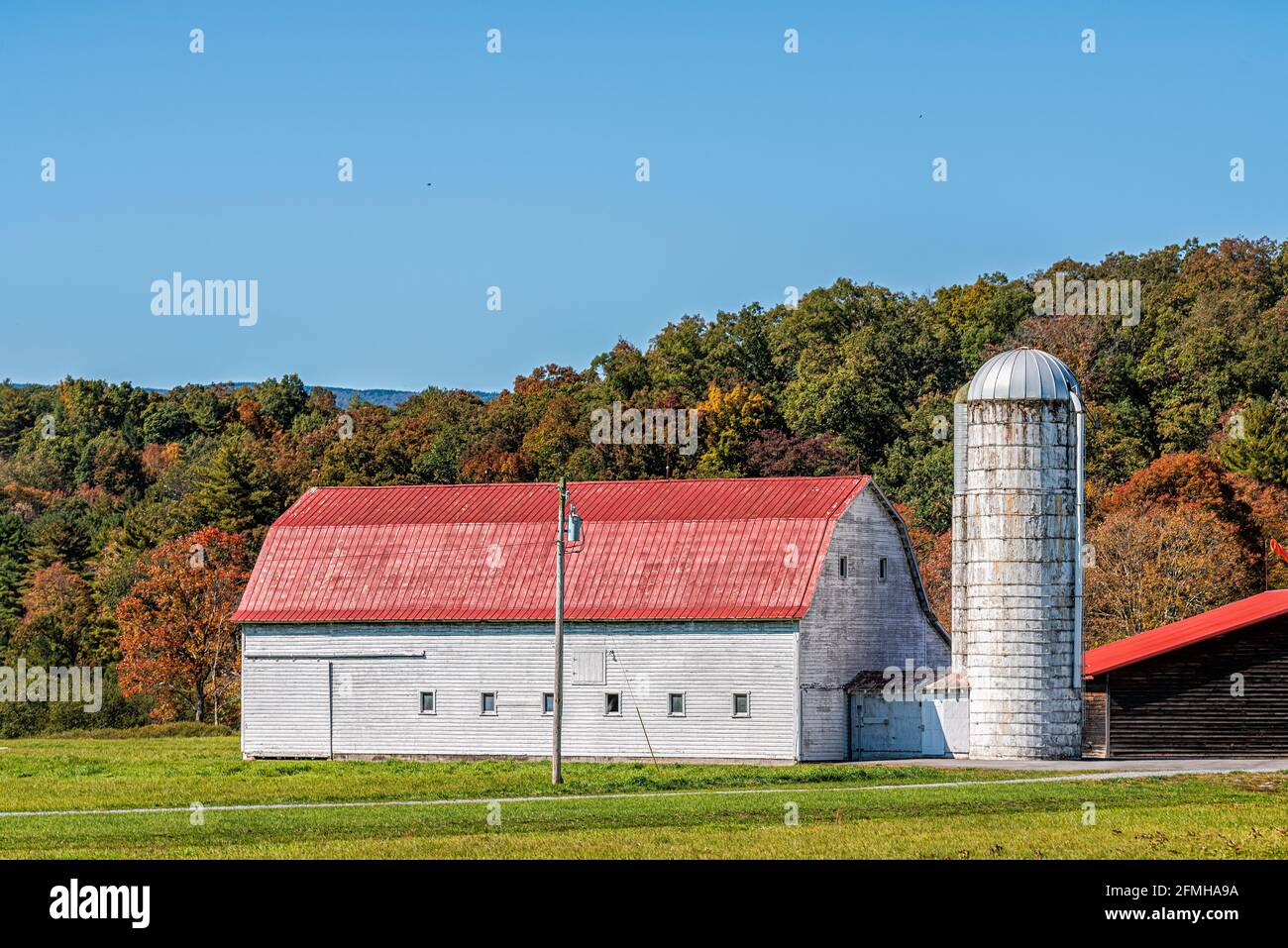 Landschaftsansicht des Bauernhofes in West Virginia mit roter Ernte Getreidelager Silogebäude und Scheune Schuppen von grünem Gras Feld mit Allegheny Mountains Wald Stockfoto