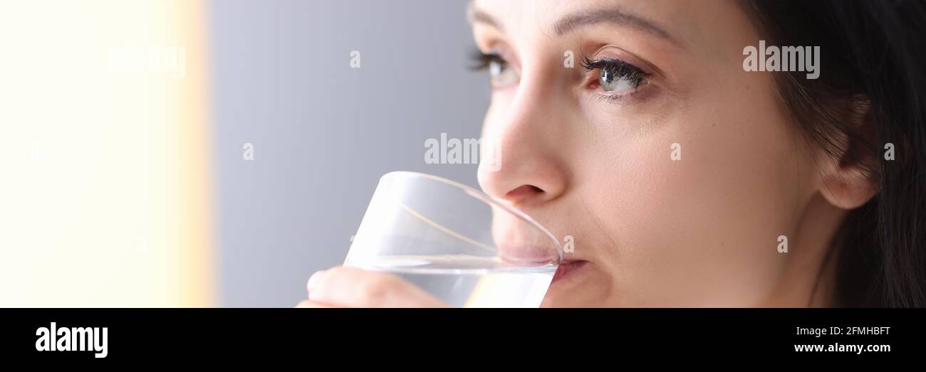 Junge Frau hält Glas in den Händen und trinkt Wasser Von ihm Stockfoto