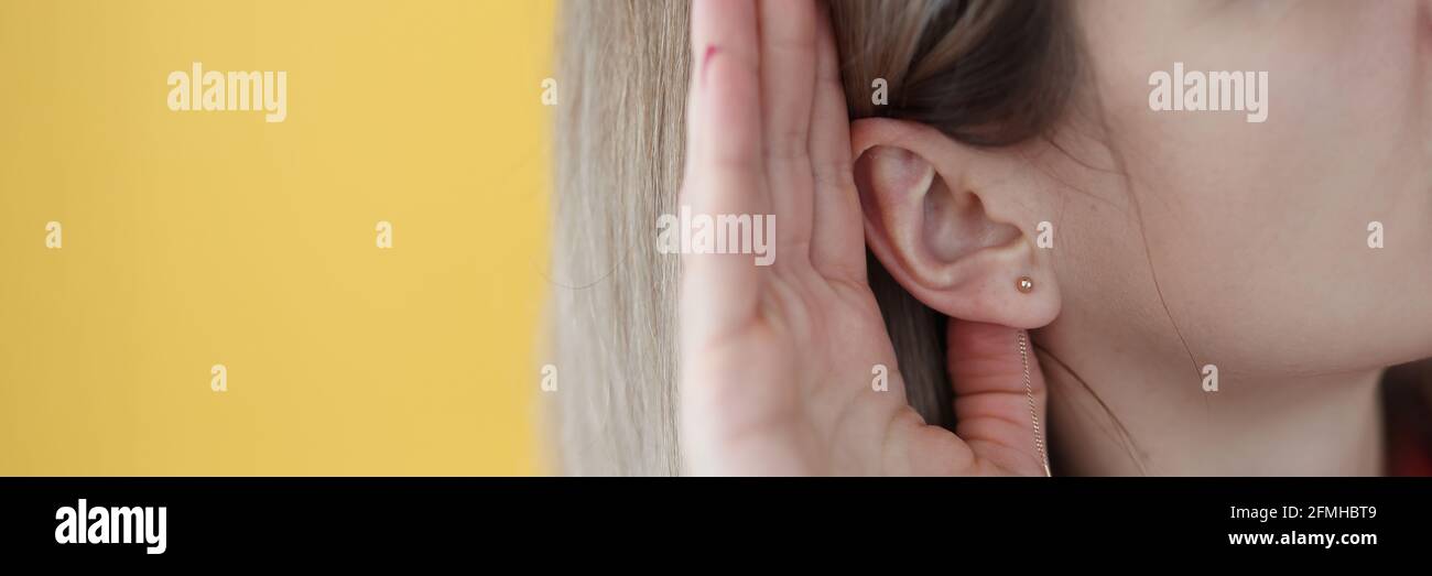 Junge hörharte Frau, die ihre Hand nahe dem Ohr hält Stockfoto