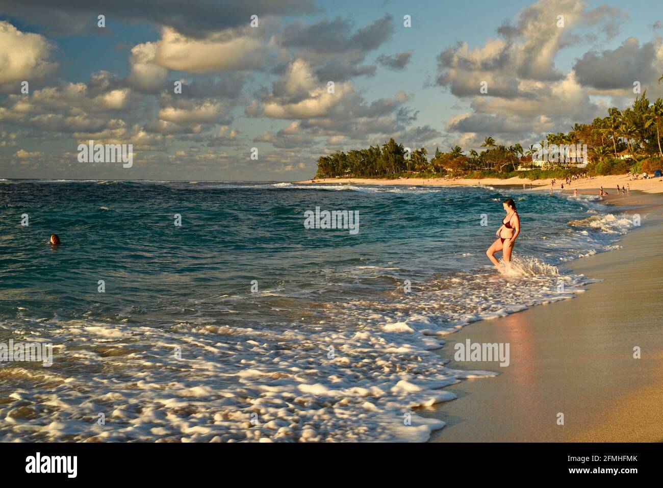 Attraktive junge Freundinnen, die im warmen Wasser mit starker Flut und Strömung plantschen und schwimmen, Sunset Beach, North Shore, Haleiwa, Hawaii, USA Stockfoto