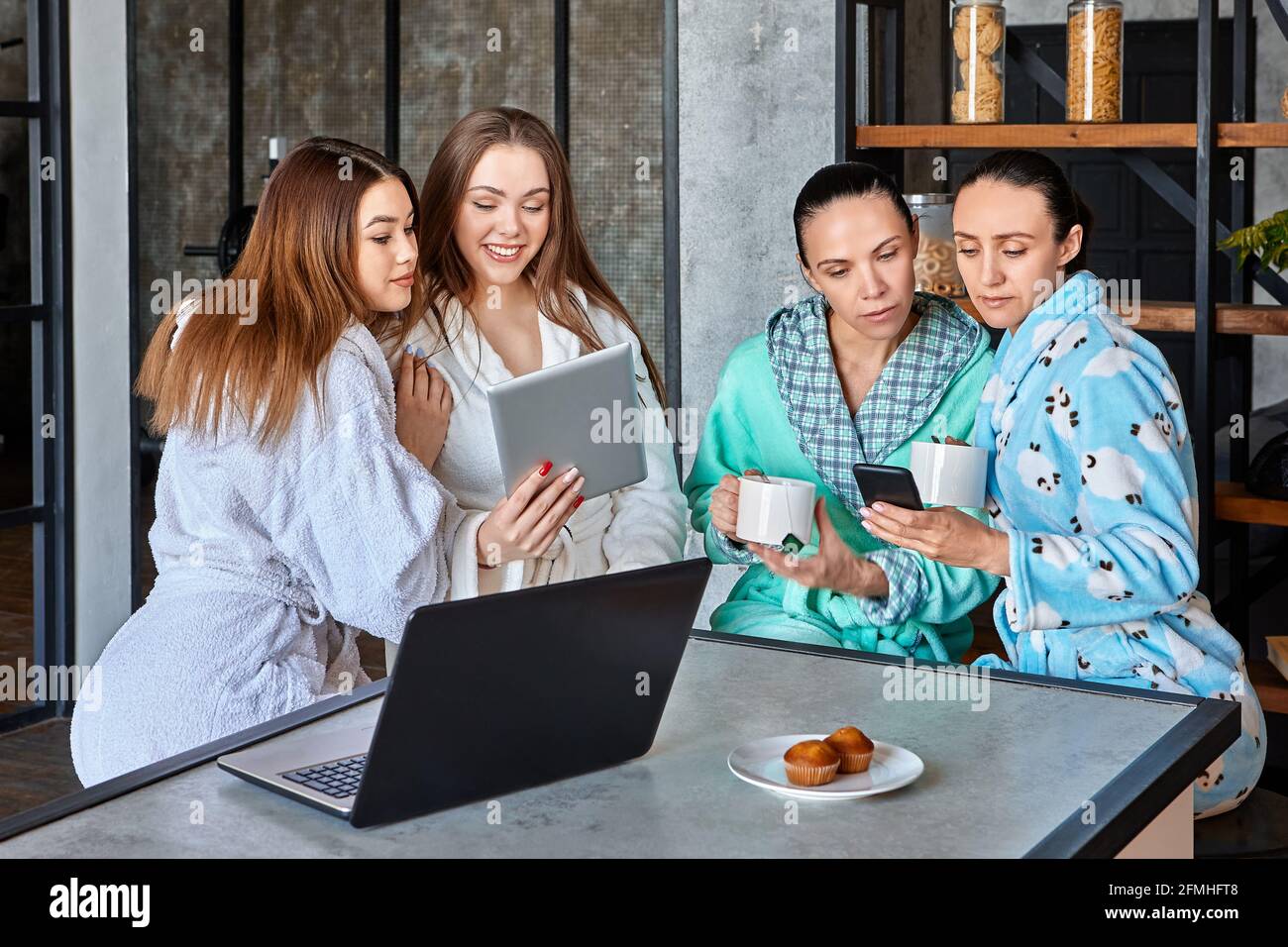 Beim Frühstück sehen sich eine Gruppe von Frauen Nachrichten und Nachrichten auf mobilen Geräten an und sitzen am Tisch im Speisesaal. Stockfoto