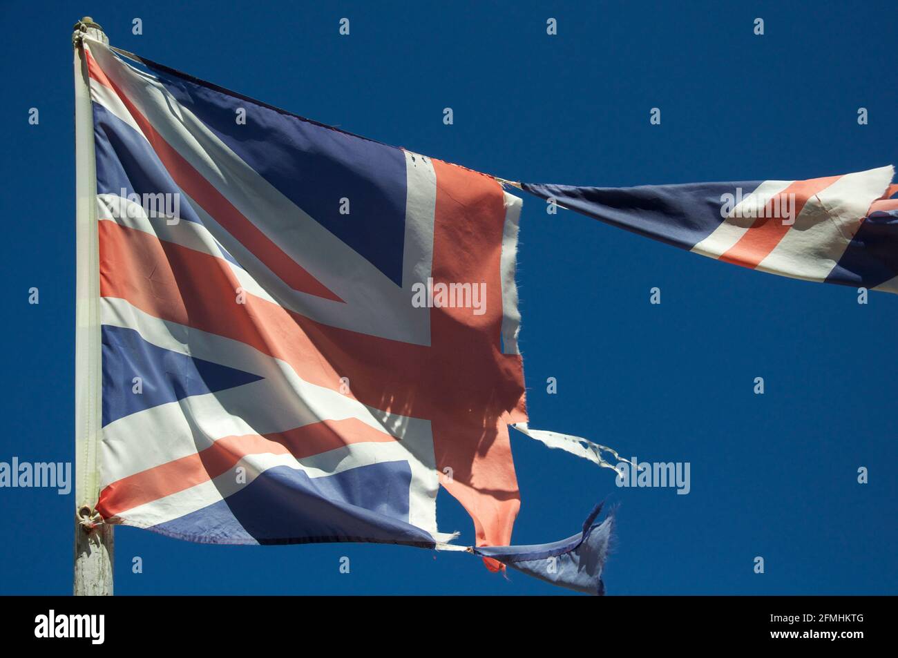 Alt und verblasst. Die Unionsflagge des Vereinigten Königreichs zerflattert und zerrissen, flattert und flattert im Wind gegen den Himmel. England, Großbritannien, Großbritannien. Stockfoto