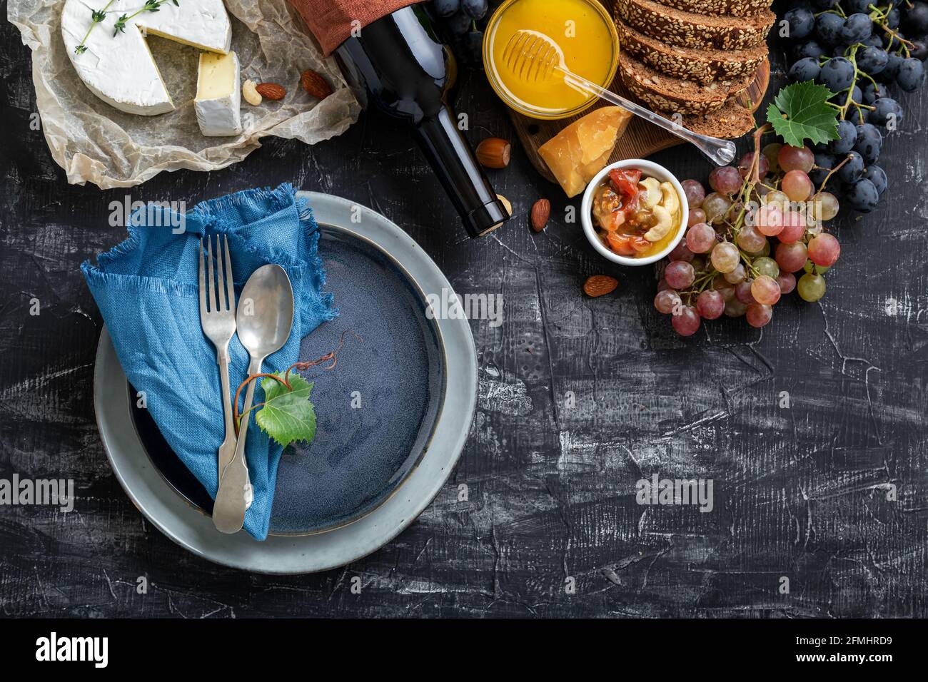 Leere Portion blauen Teller mit Gabellöffel in Rahmen von Lebensmitteln Zutaten mediterrane Küche. Blaue Teller Schale im Rahmen von Lebensmitteln Wein Käse mit Kopie Stockfoto