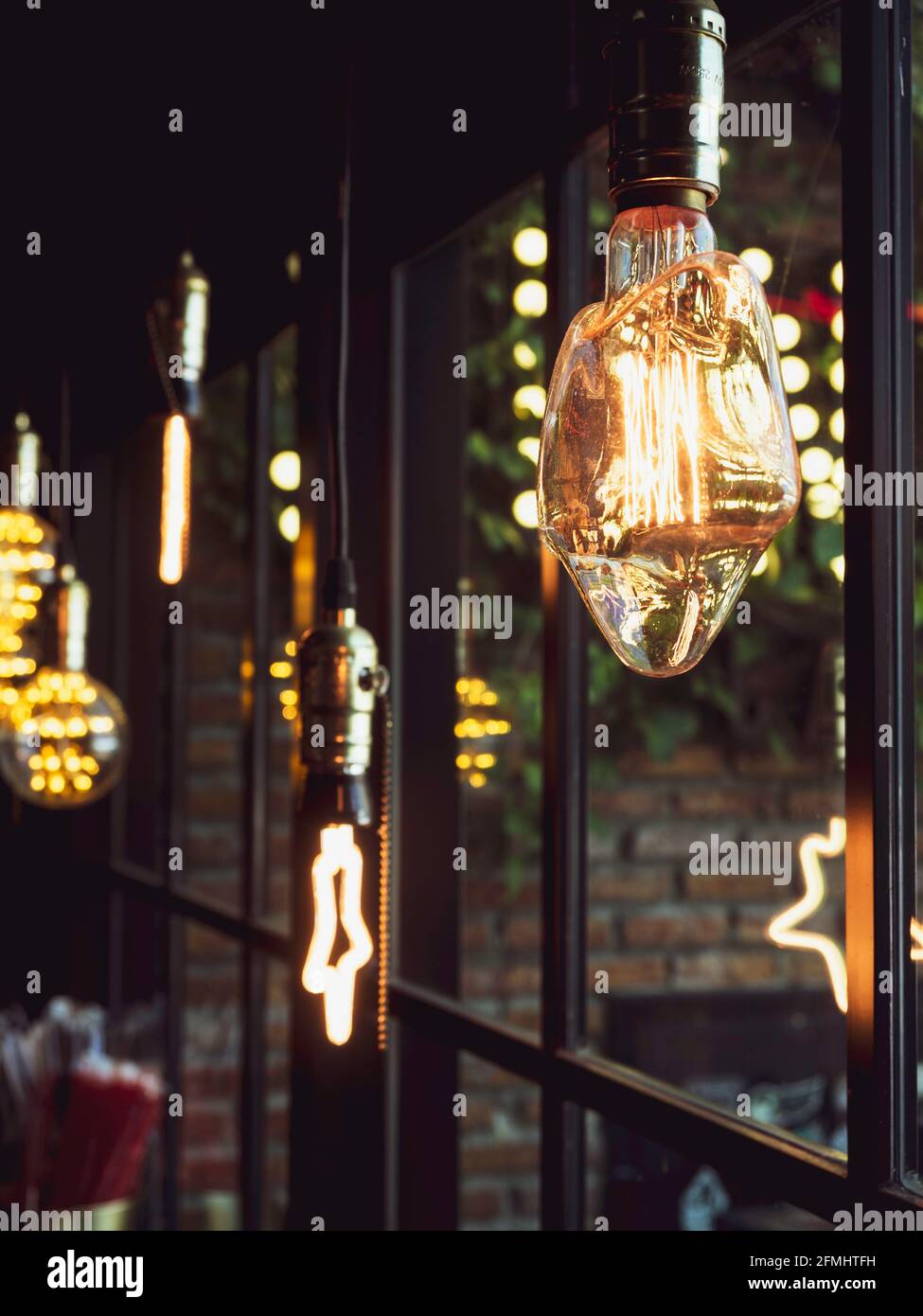 Sternförmige Dekoration von Glühbirnen im Café. Viele LED-Lampen im  Retro-Stil, die im dunklen Hintergrund nahe dem Glasfenster leuchten, im  vertikalen Stil Stockfotografie - Alamy