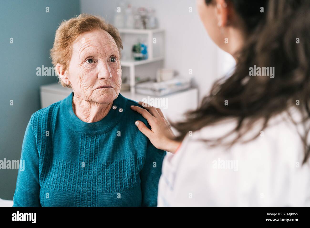 Crop anonymen Arzt im Gespräch mit Angst traurigen älteren Frau beim Blick auf einander während der Untersuchung im Krankenhaus Stockfoto
