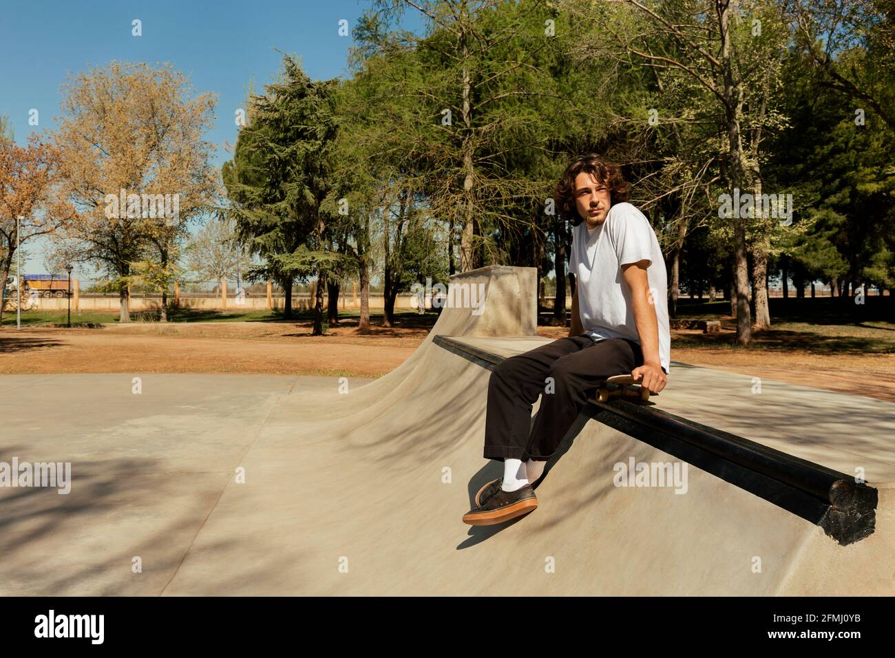 Junger Mann, der auf dem Skateboard sitzt, um sich auszuruhen Stockfoto