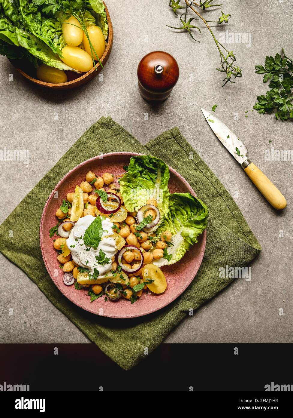 Draufsicht auf appetitliche Kichererbsen mit Burrata-Käse und verschiedenen Sorten Gemüse und Kräuter werden auf dem Tisch serviert Stockfoto