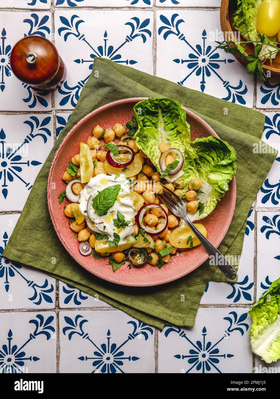 Draufsicht auf appetitliche Kichererbsen mit Burrata-Käse und verschiedenen Sorten Gemüse und Kräuter werden auf dem Tisch serviert Stockfoto